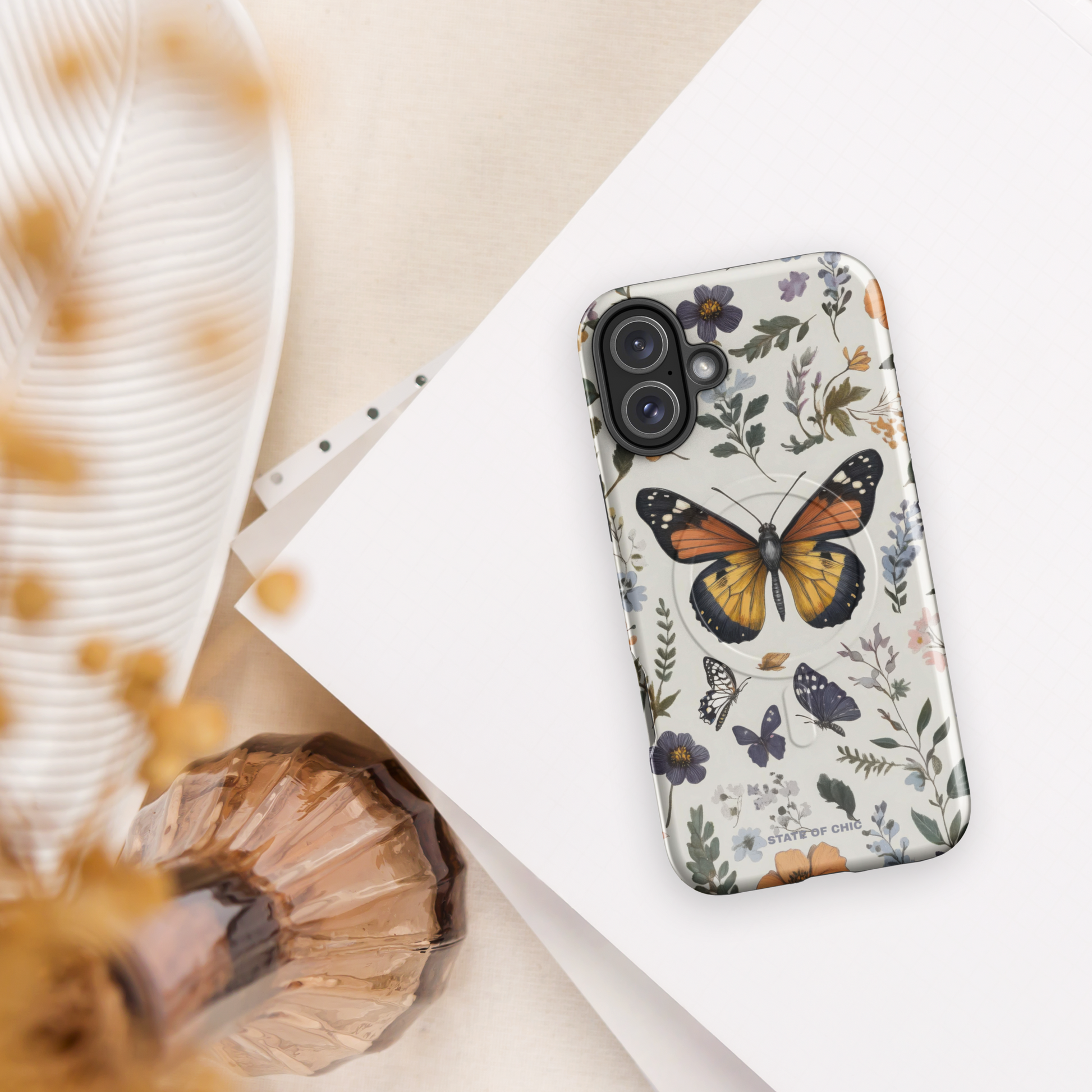 Stylish floral and butterfly phone case for iPhone with pastel tones and symmetrical nature-inspired artwork.